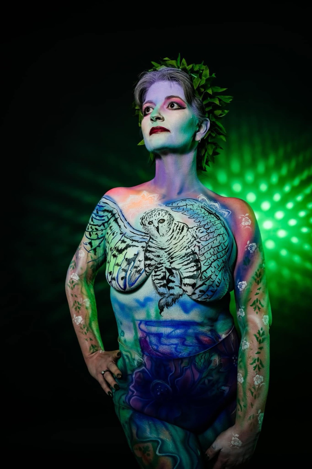 A figure in green-and-blue skeletal UV body paint under black light