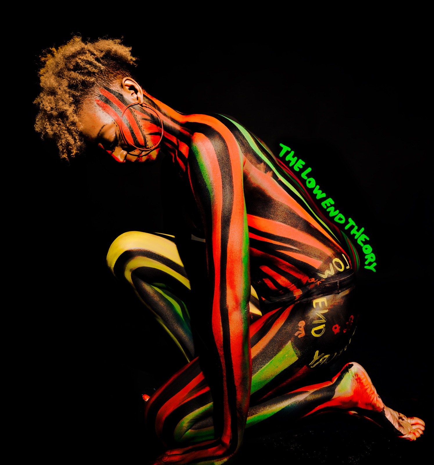 A figure in neon striped UV body paint with glowing lettering on black