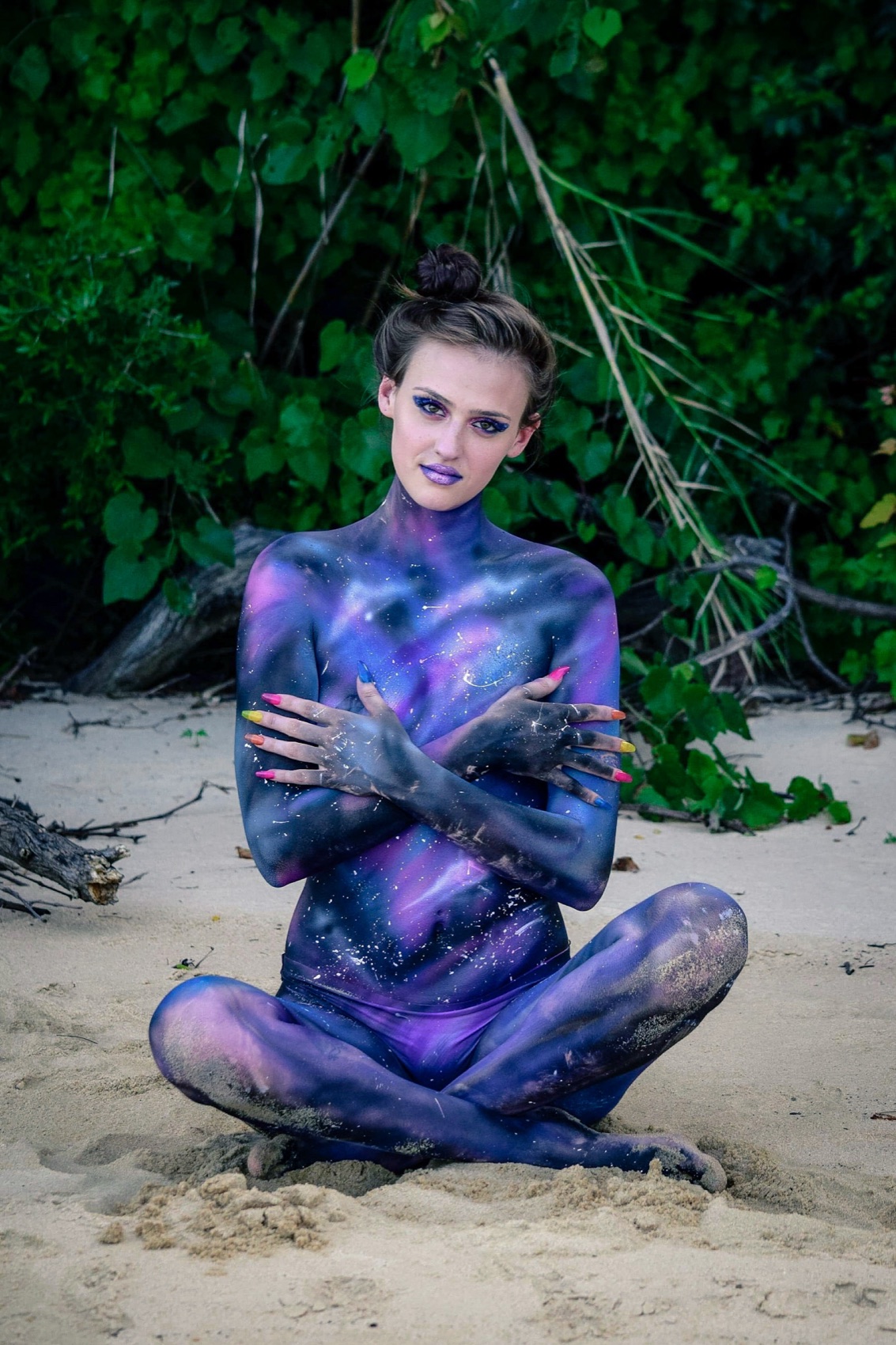 A model seated outdoors in blue and green floral body paint